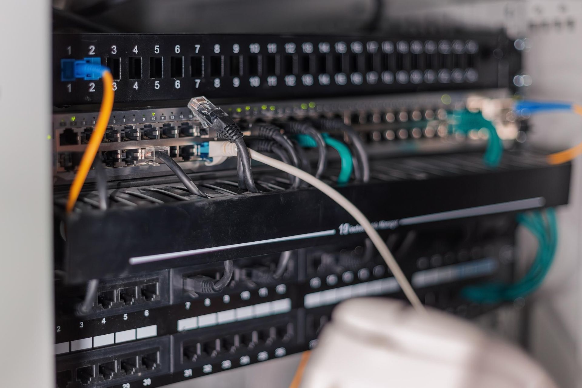 A close-up of a network server rack with various colored ethernet cables plugged into switch ports.