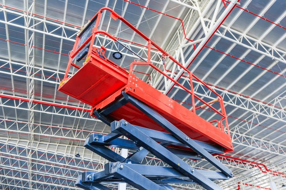 A Red Scissor Lift is Sitting in the Ceiling of a Building — Innisfail Auto Electrics Pty Ltd in Mundoo, QLD