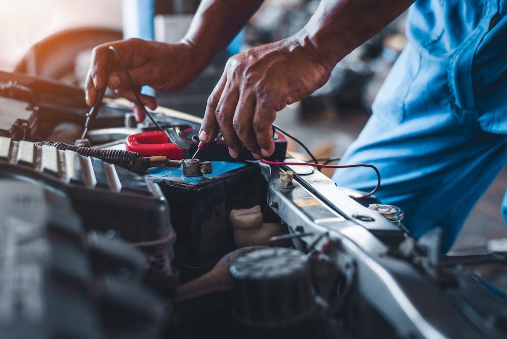 A Man is Working on a Car Battery in a Garage — Innisfail Auto Electrics Pty Ltd in Tully, QLD