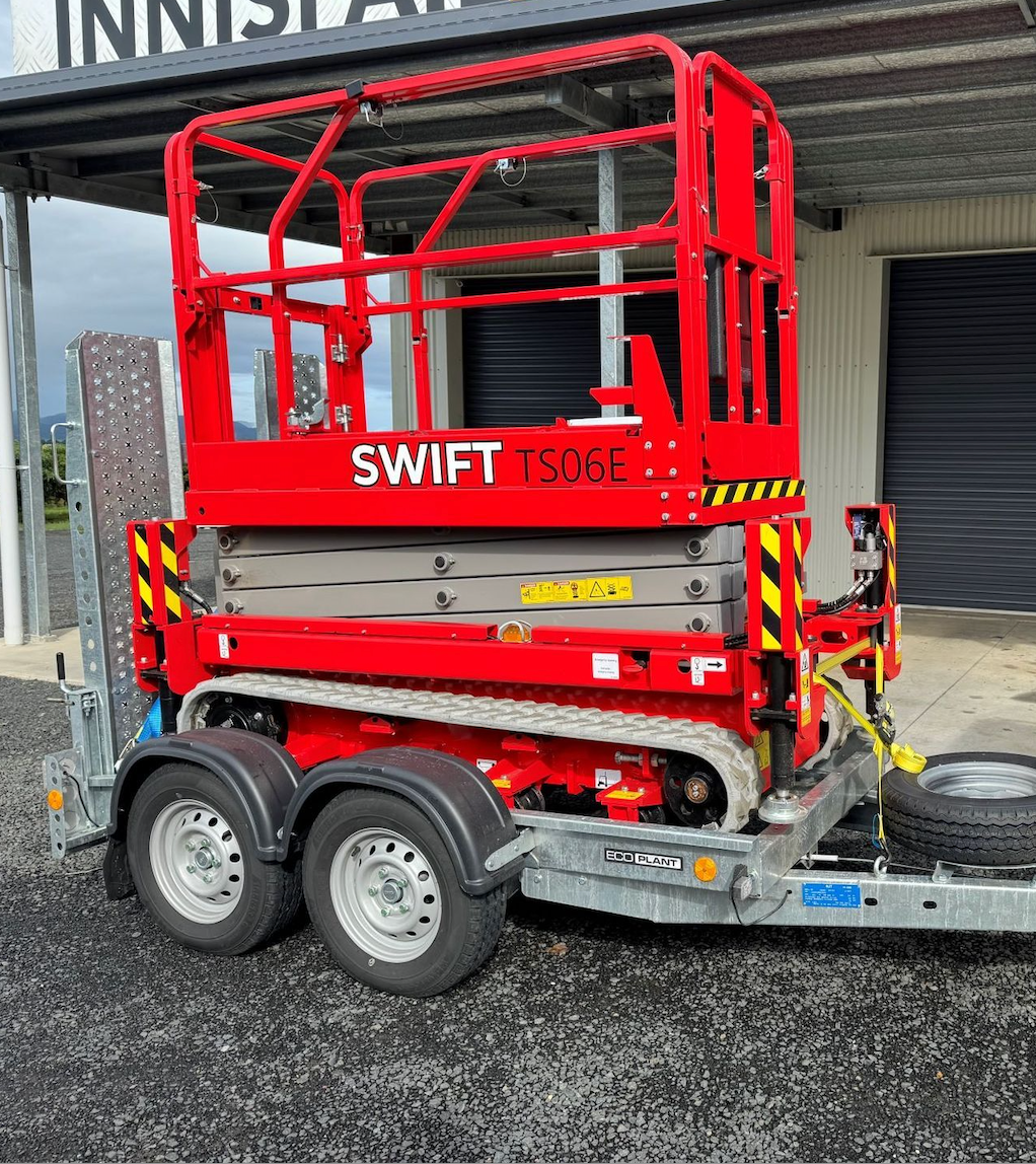 A Red Scissor Lift is on a Trailer in Front of a Building — Innisfail Auto Electrics Pty Ltd in Mundoo, QLD