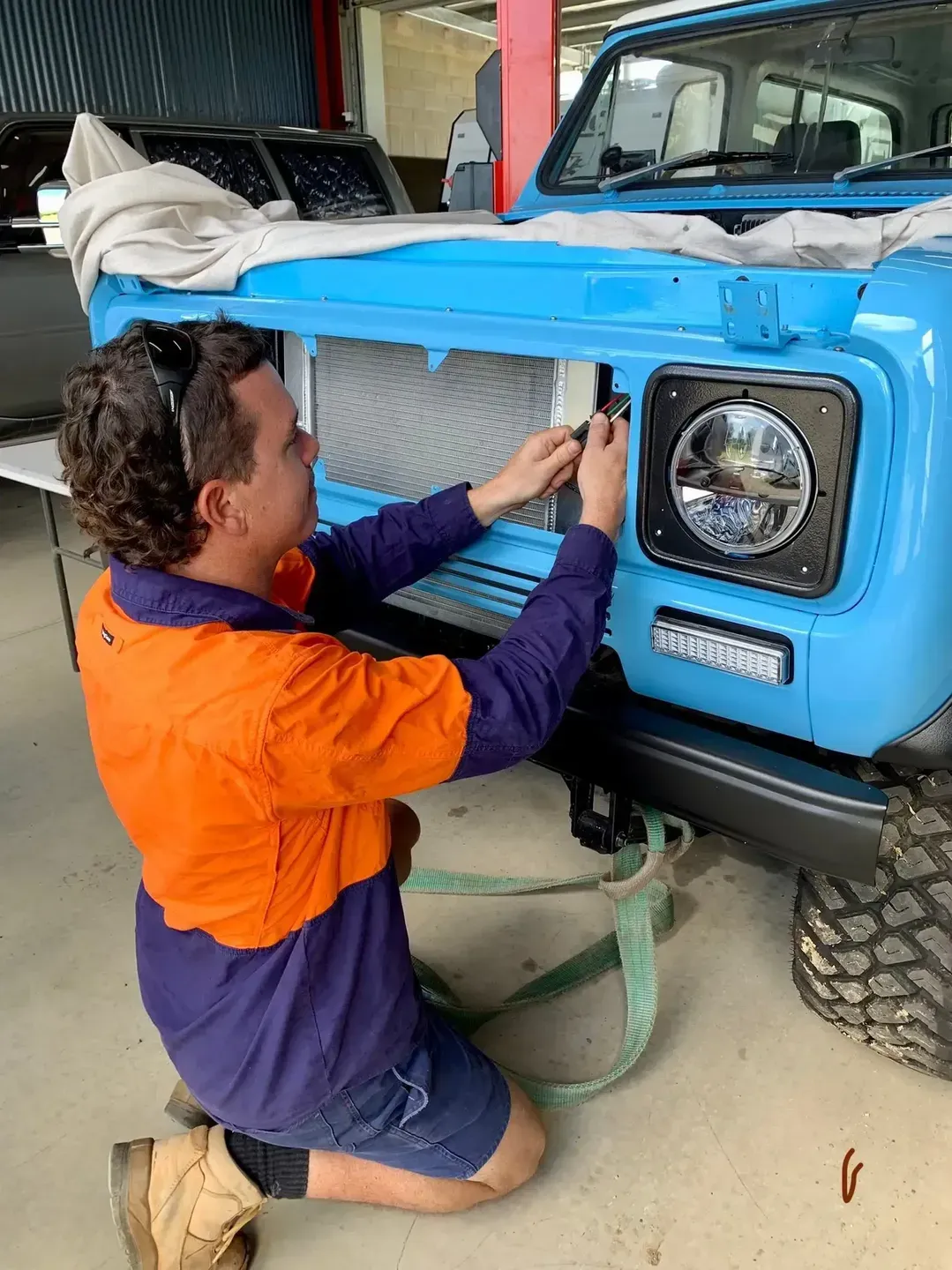 Car Mechanic Working on a Blue 4WD — Innisfail Auto Electrics Pty Ltd in Mundoo, QLD