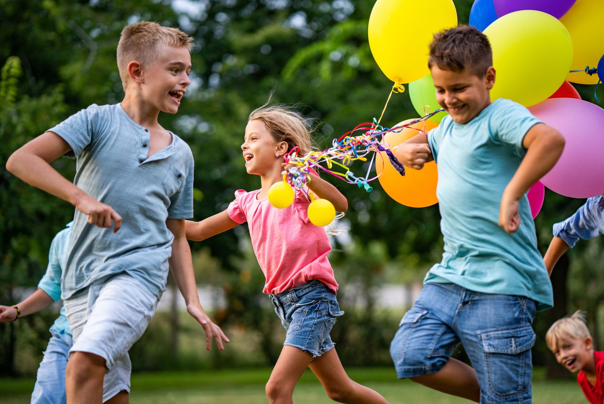 A group of children are playing with balloons in a park.