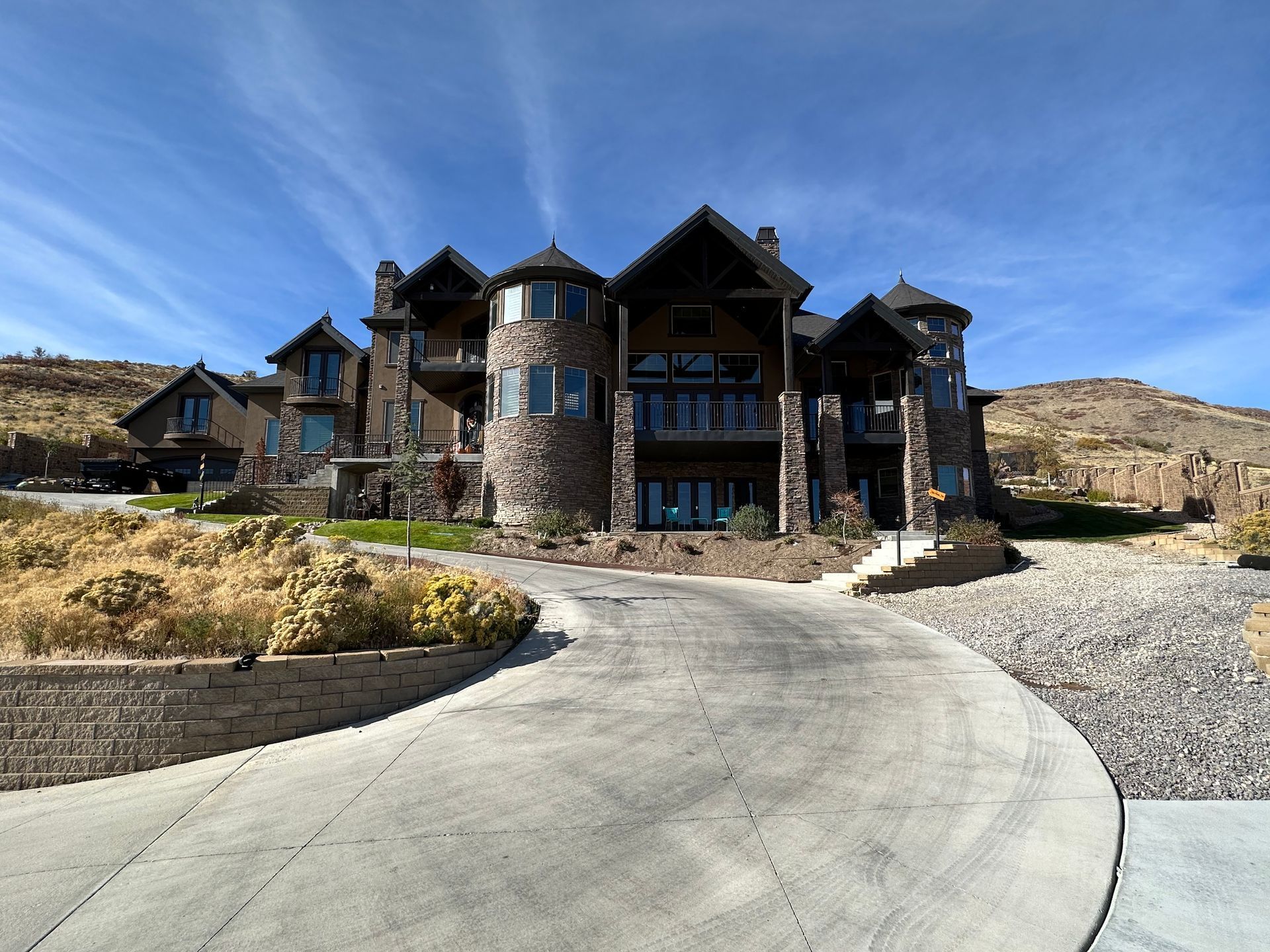 A large house is sitting on top of a hill with a driveway leading to it.