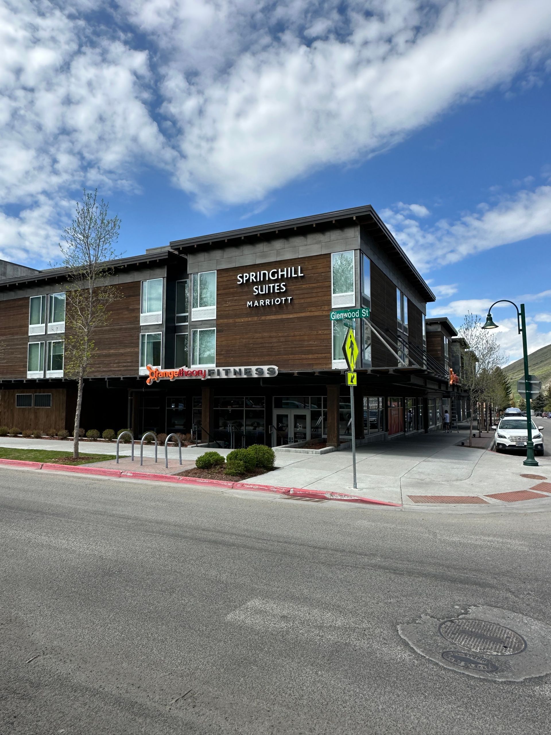 A large building with a lot of windows is on the corner of a street.