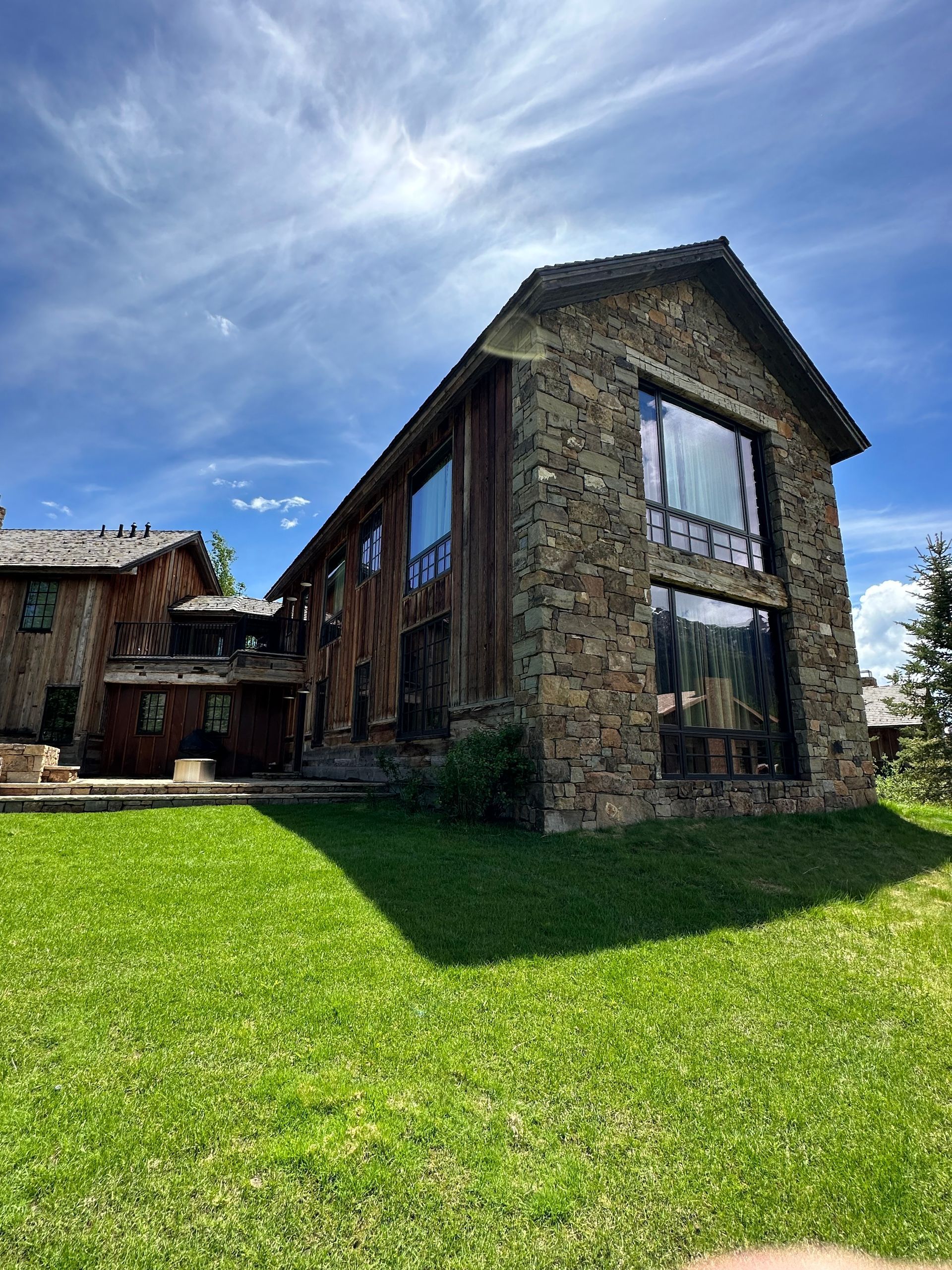 A large stone building with a lot of windows is sitting in the middle of a lush green field.