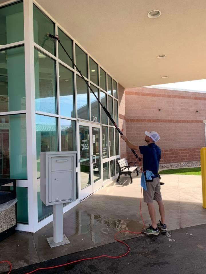 A man is cleaning the windows of a building with a high pressure washer.