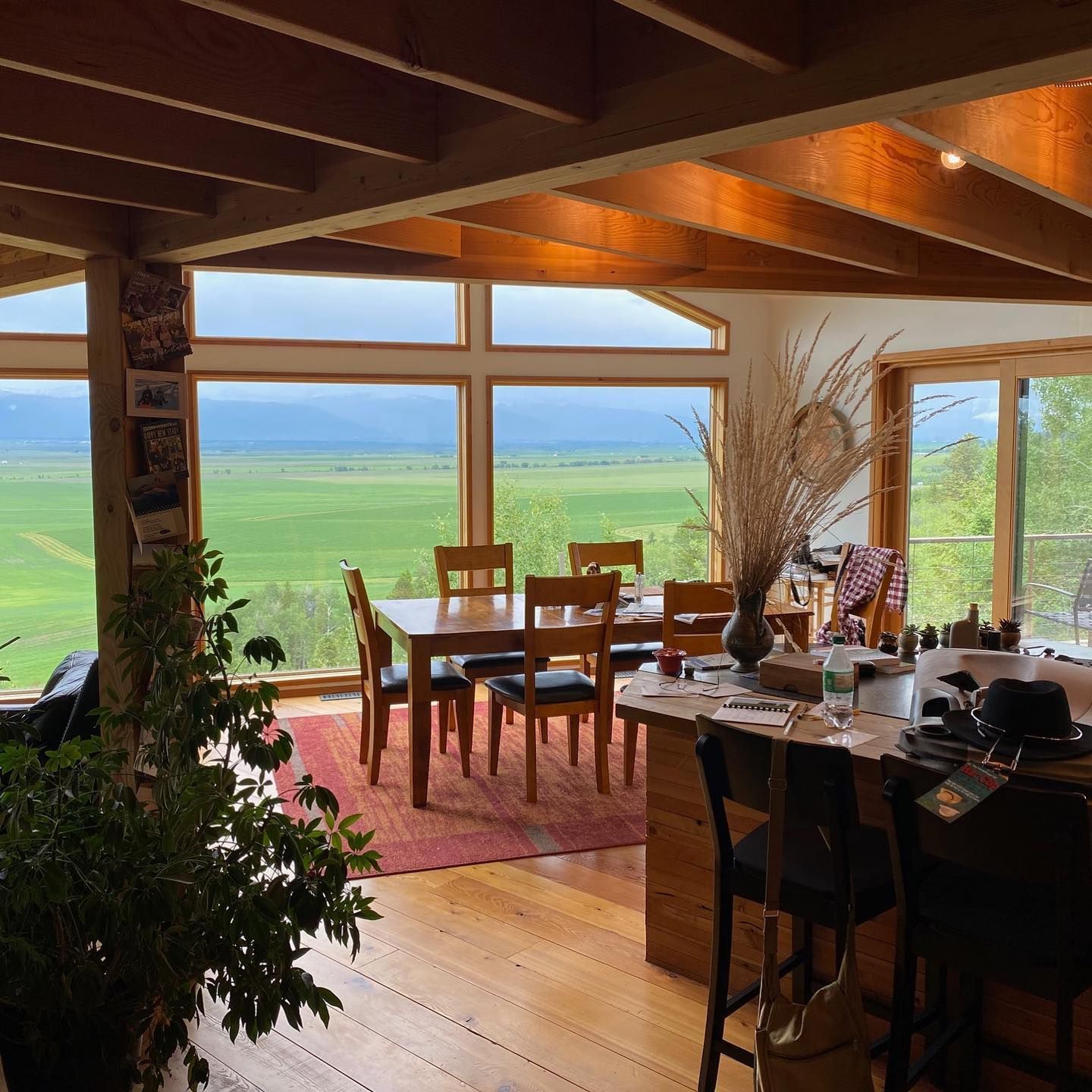 A dining room with a table and chairs and a view of a field.
