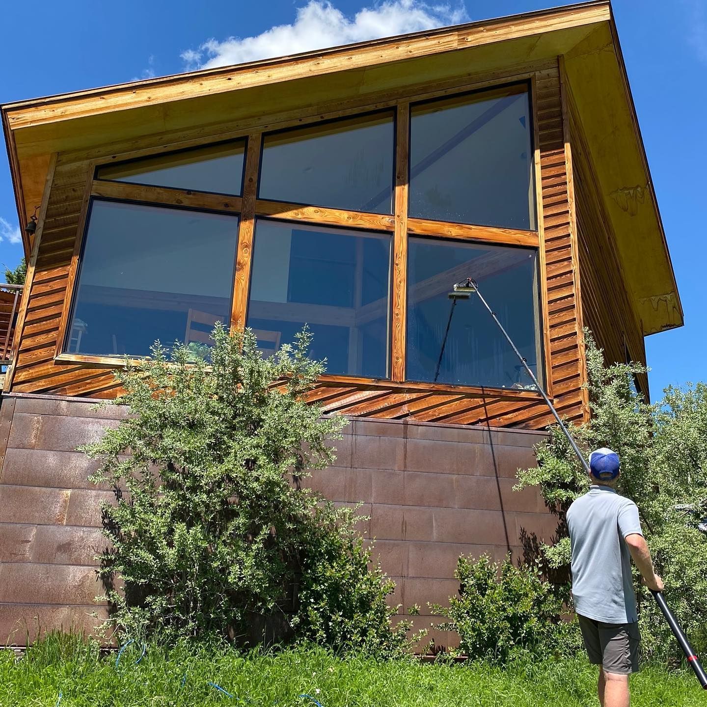 A man is cleaning the windows of a wooden house