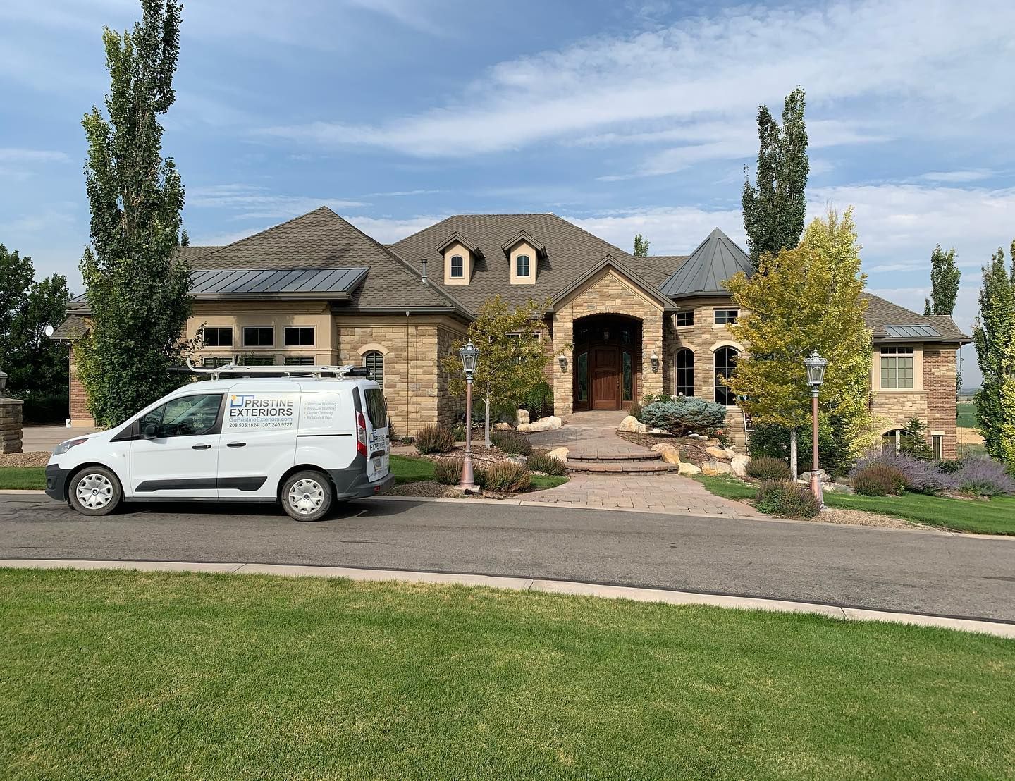 A white van is parked in front of a large house.