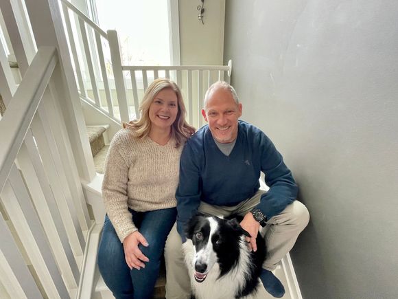 A man and a woman are sitting on a set of stairs with a dog.