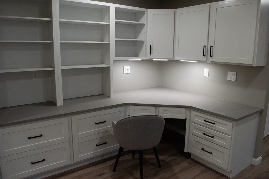 A corner desk with a chair and shelves in a room.