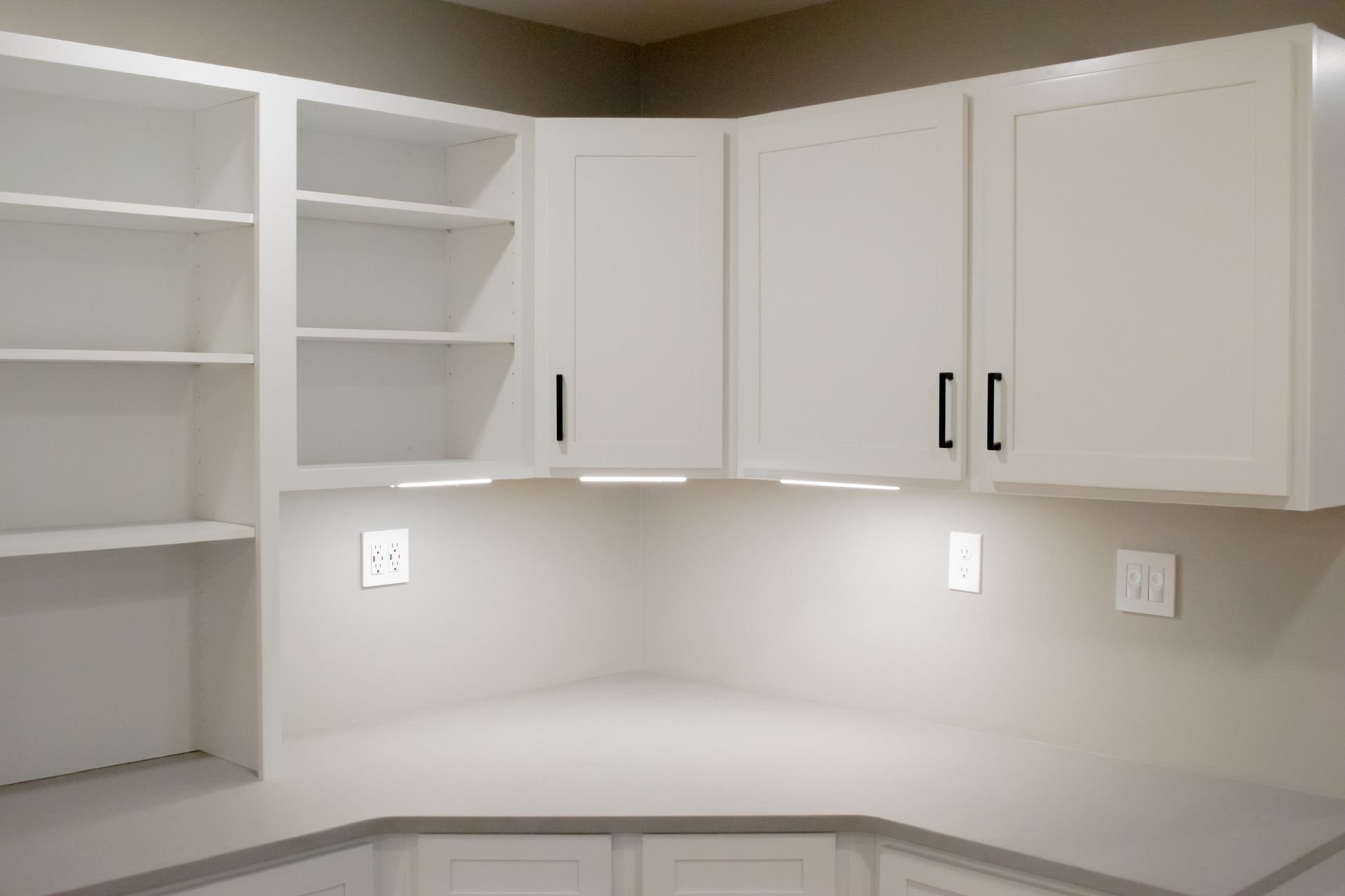 A corner of a kitchen with white cabinets and shelves