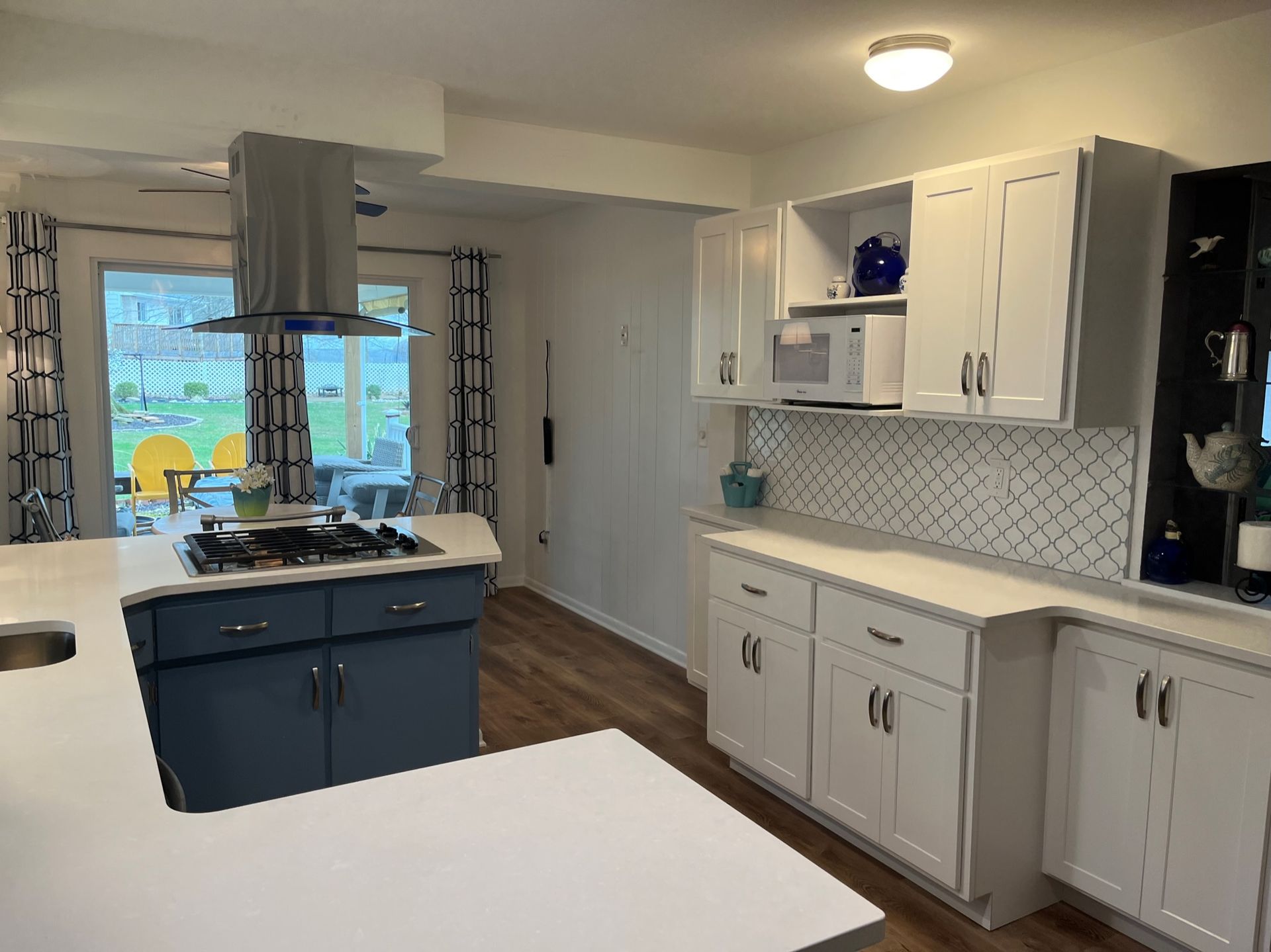 A kitchen with blue cabinets and white counter tops and a stove top oven.