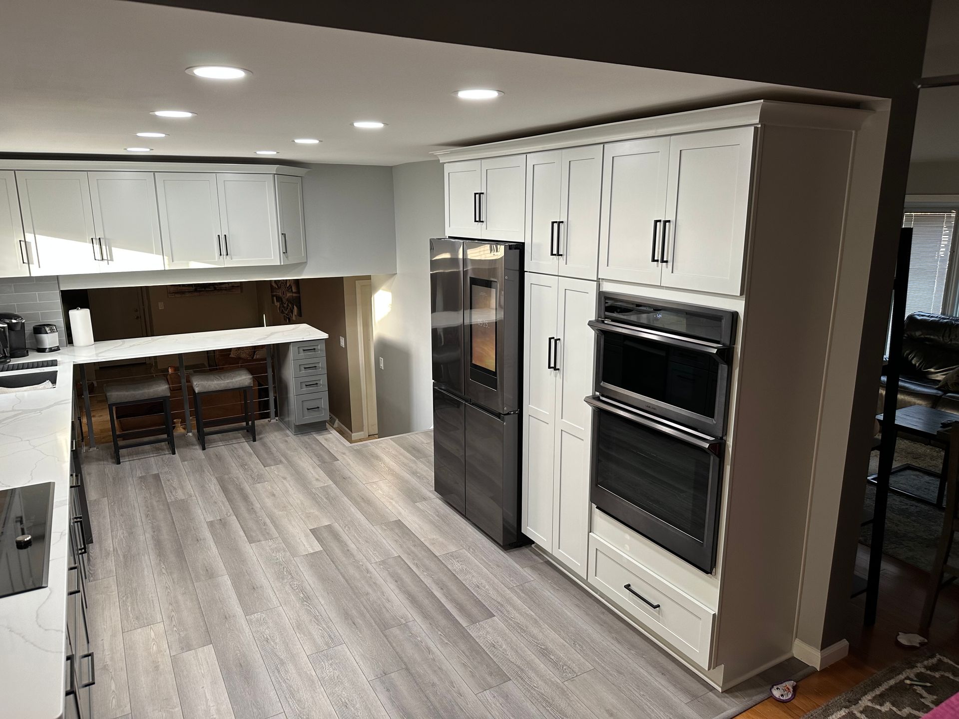 A kitchen with white cabinets , stainless steel appliances and hardwood floors.