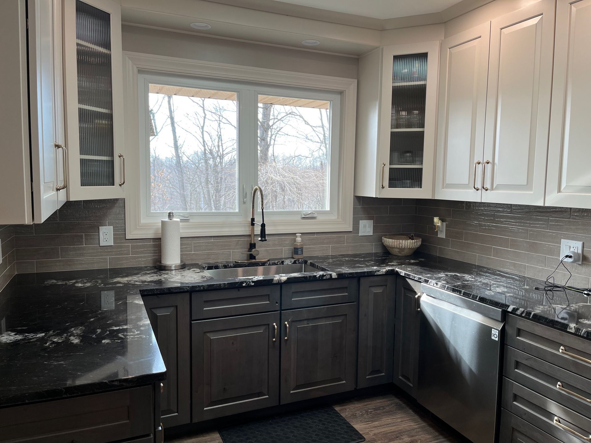 A kitchen with gray cabinets and black counter tops