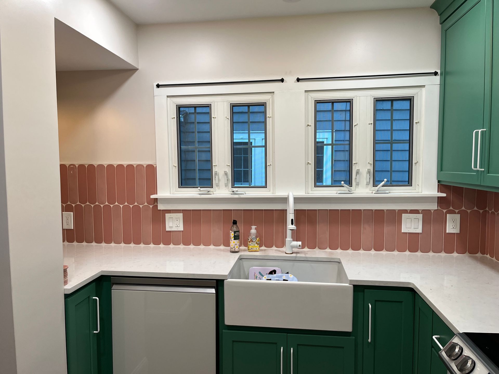 A kitchen with green cabinets and a white sink
