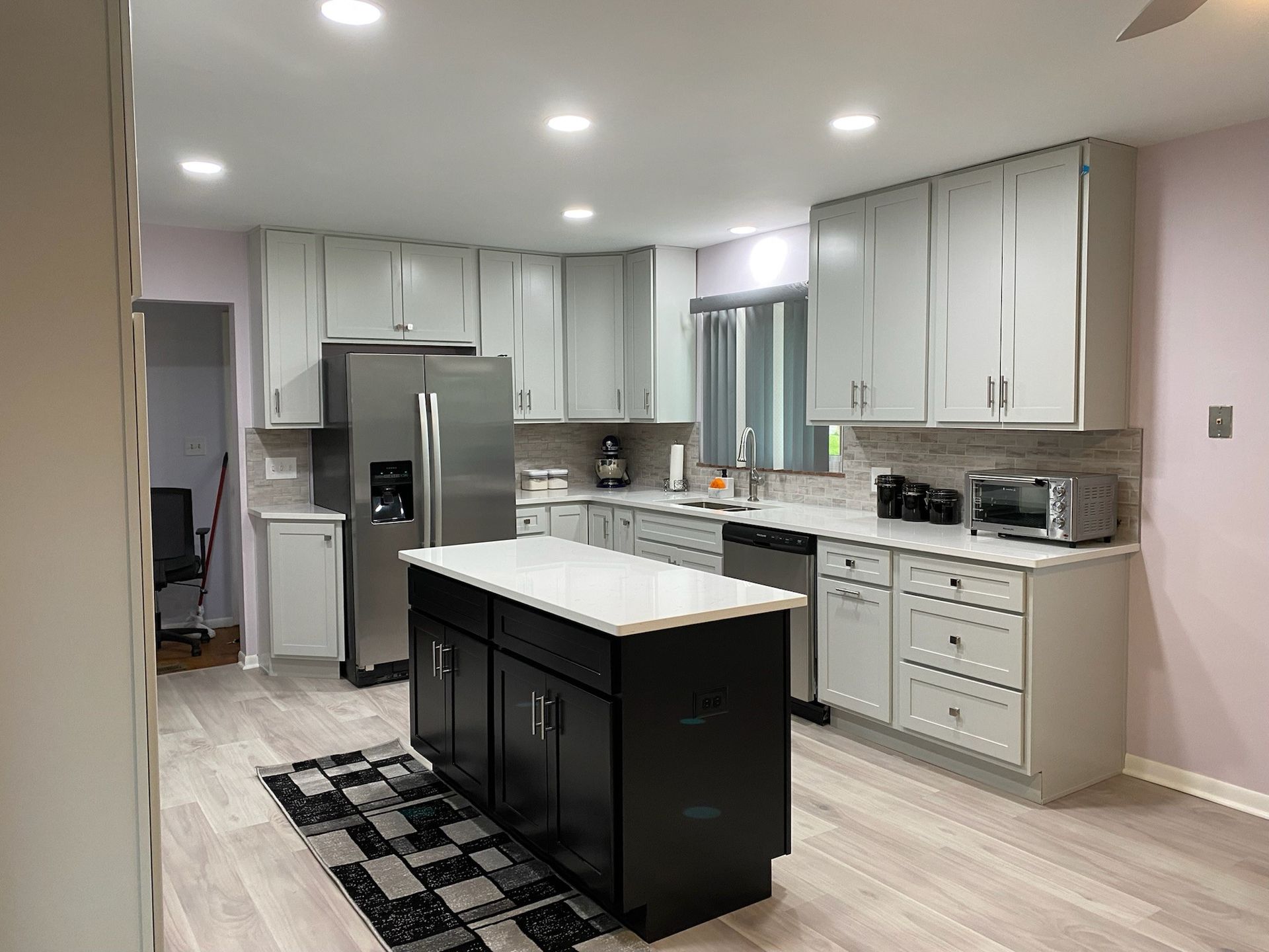 A kitchen with white cabinets , stainless steel appliances , and a large island.
