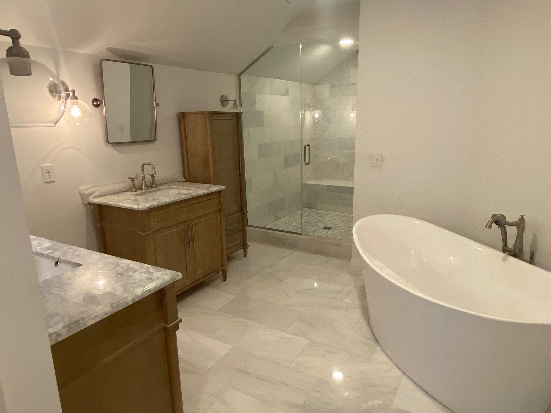 A bathroom with two sinks , a tub , and a walk in shower.