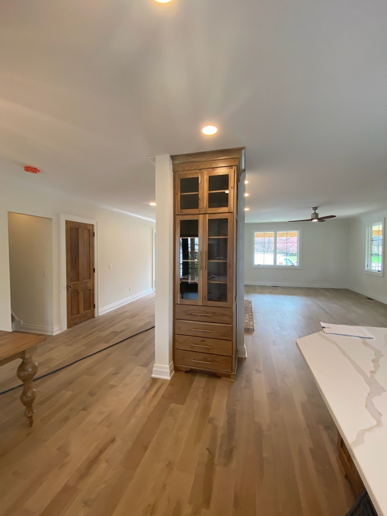 Wooden cabinet dividing an open-plan space with hardwood floors and white walls.