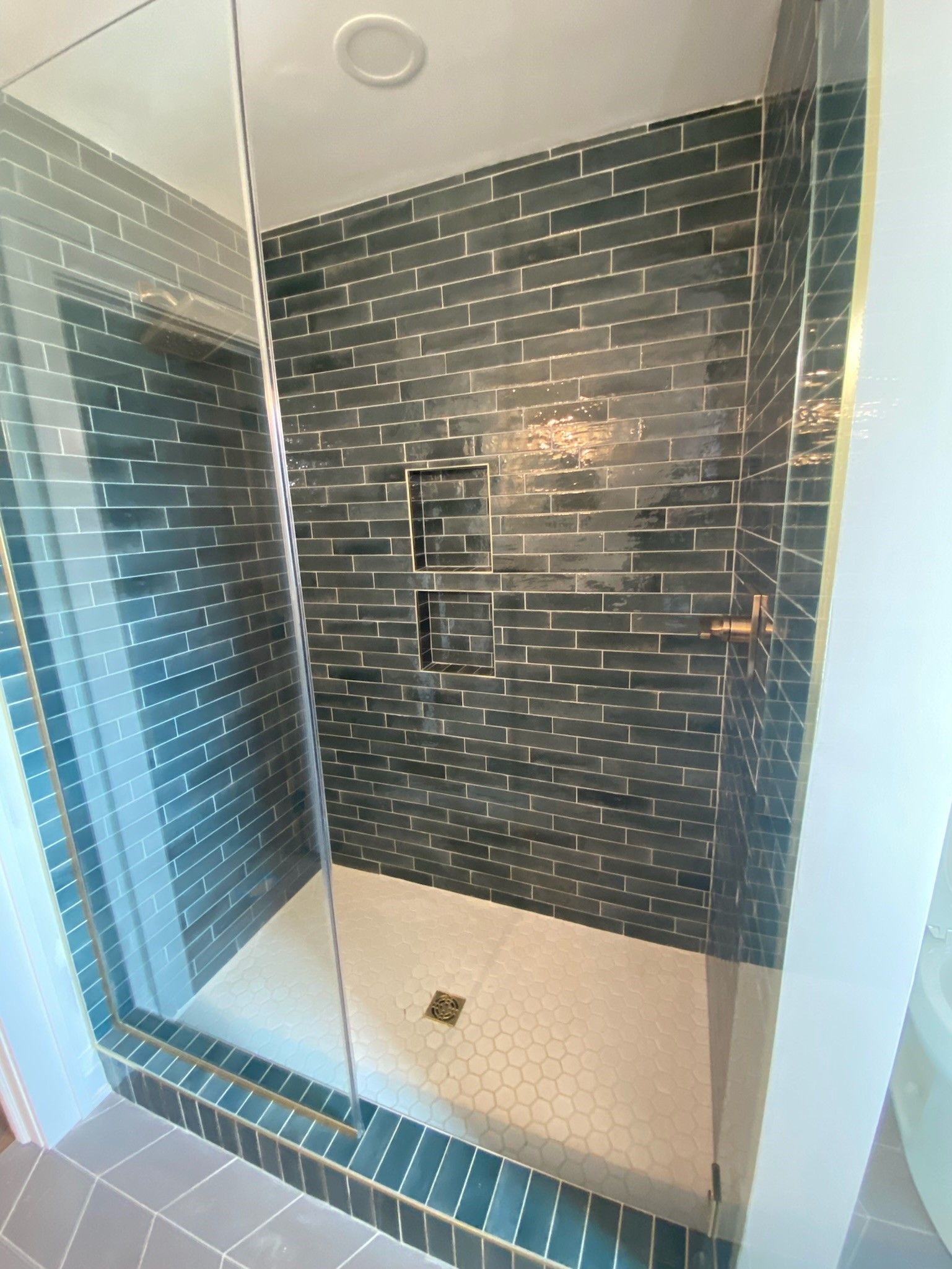 A bathroom with a walk in shower with a glass door.