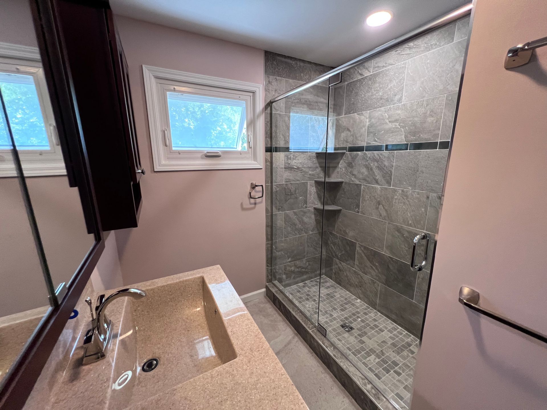 A bathroom with a sink and a walk in shower.