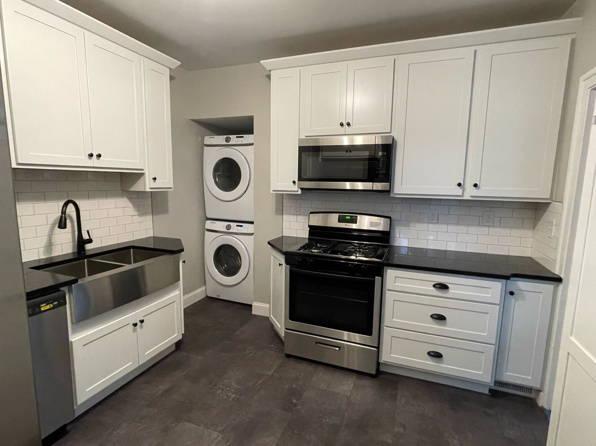 A kitchen with white cabinets , stainless steel appliances , a sink , and a stove.