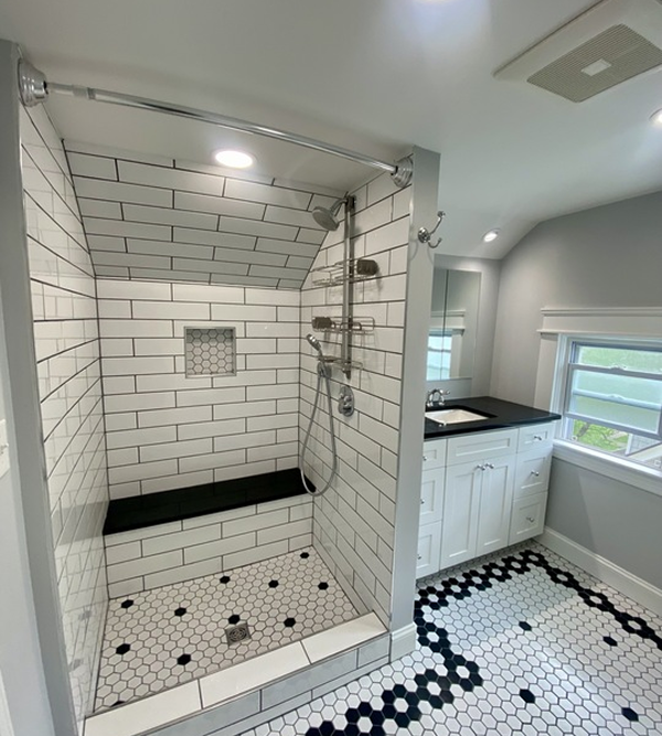 A bathroom with a walk in shower and a black and white tile floor.