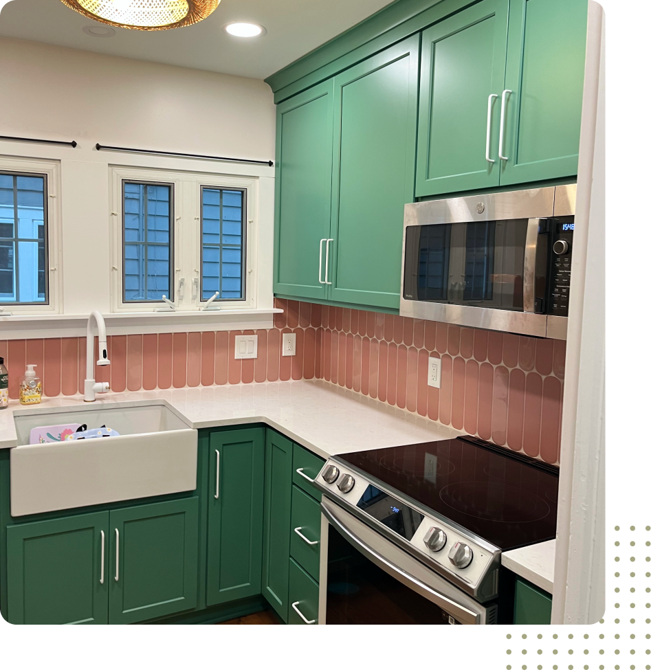 A kitchen with green cabinets , a sink , a stove , and a microwave.