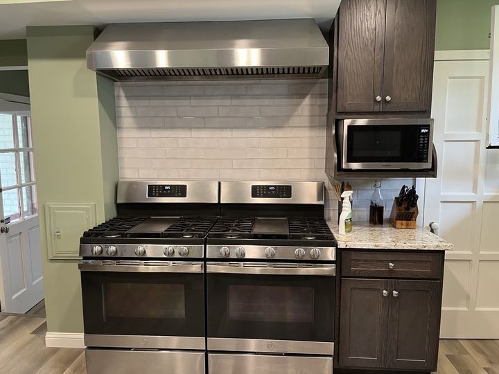 A kitchen with a stove , oven , microwave and cabinets.