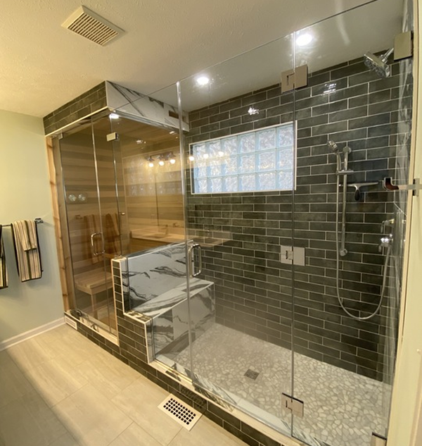 A bathroom with a walk in shower and a brick wall.