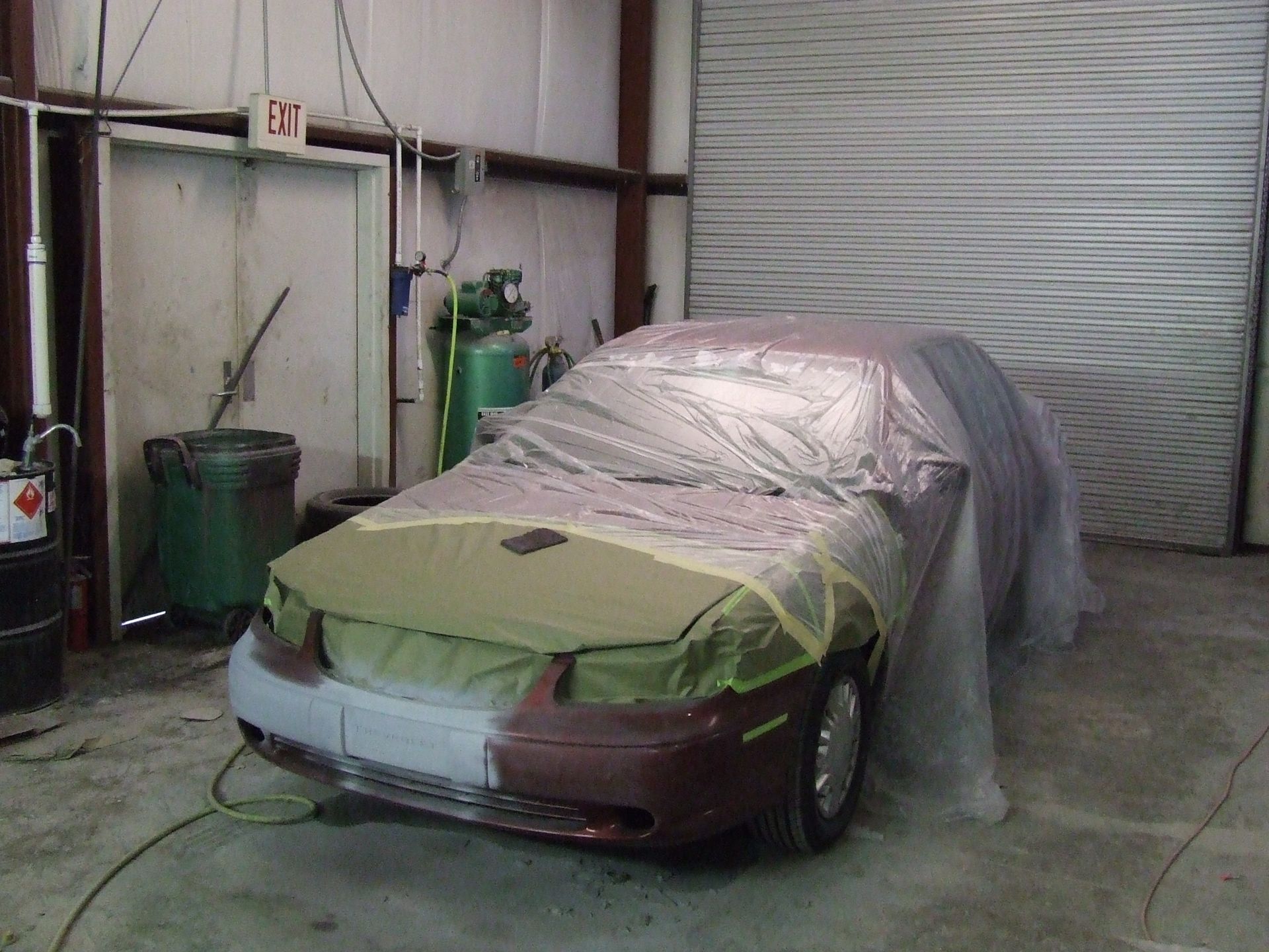 a car is covered in plastic while being painted in a garage
