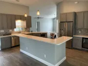 Modern kitchen with gray cabinets, white countertops, stainless steel appliances, and a breakfast bar.