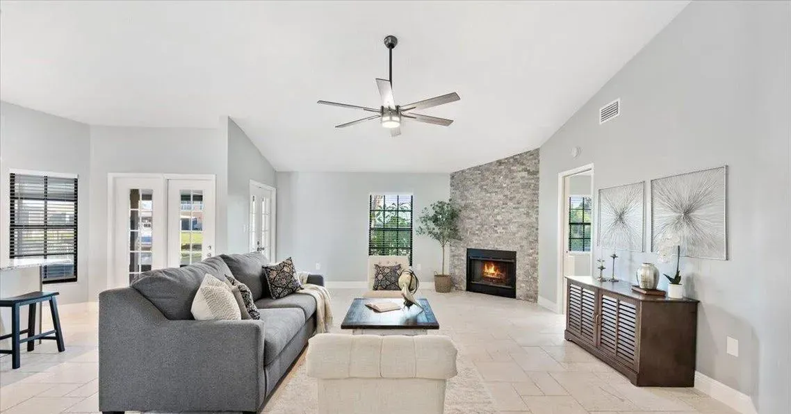 Spacious living room with gray sofa, fireplace, and beige tile floor.