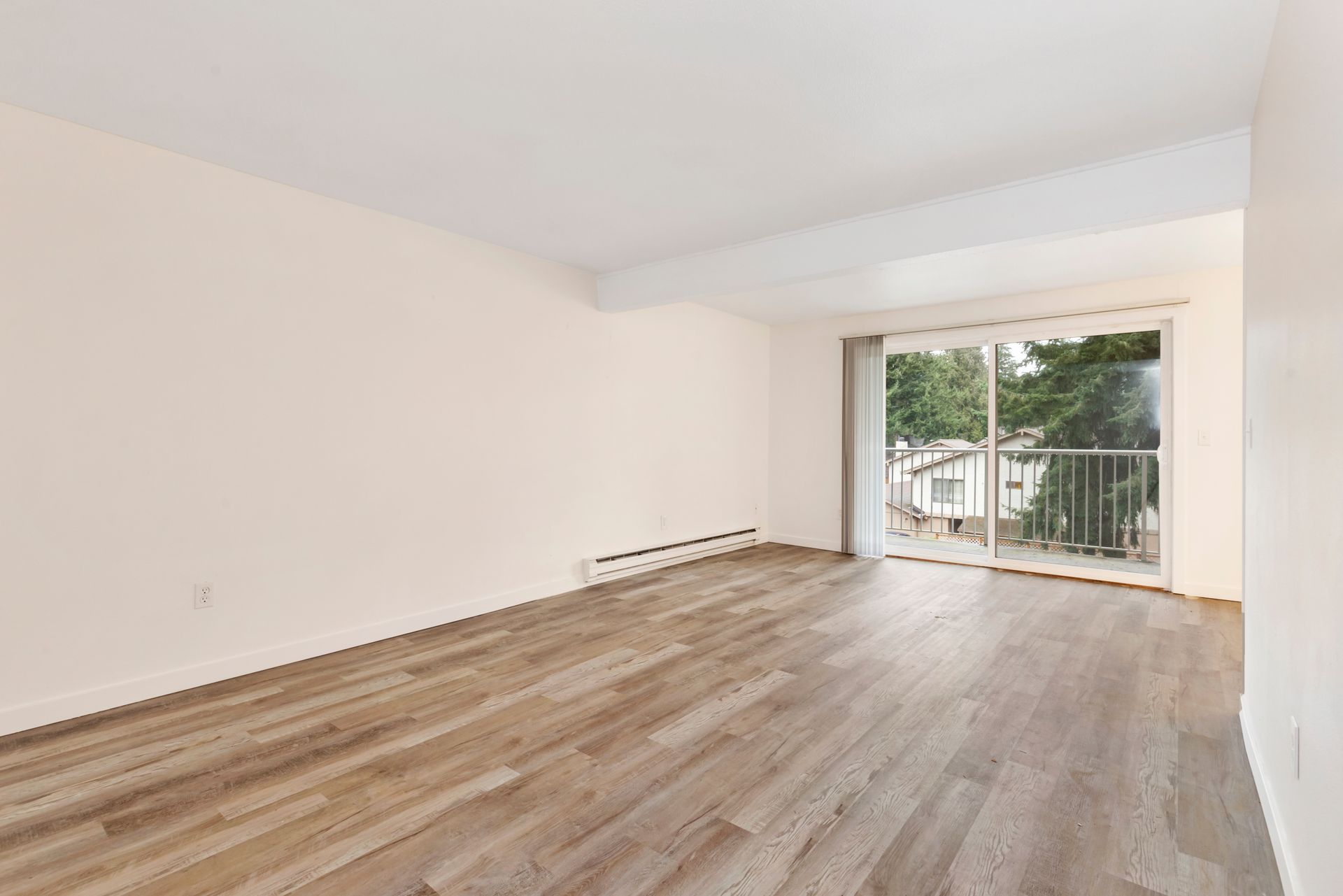 an empty living room with hardwood floors and sliding glass doors .