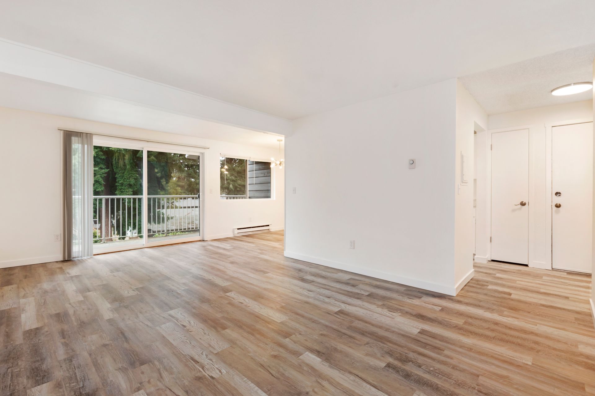 an empty living room with hardwood floors and sliding glass doors .