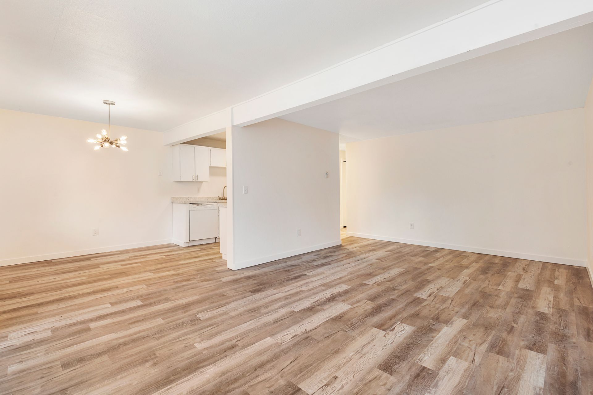 an empty living room with hardwood floors and white walls .