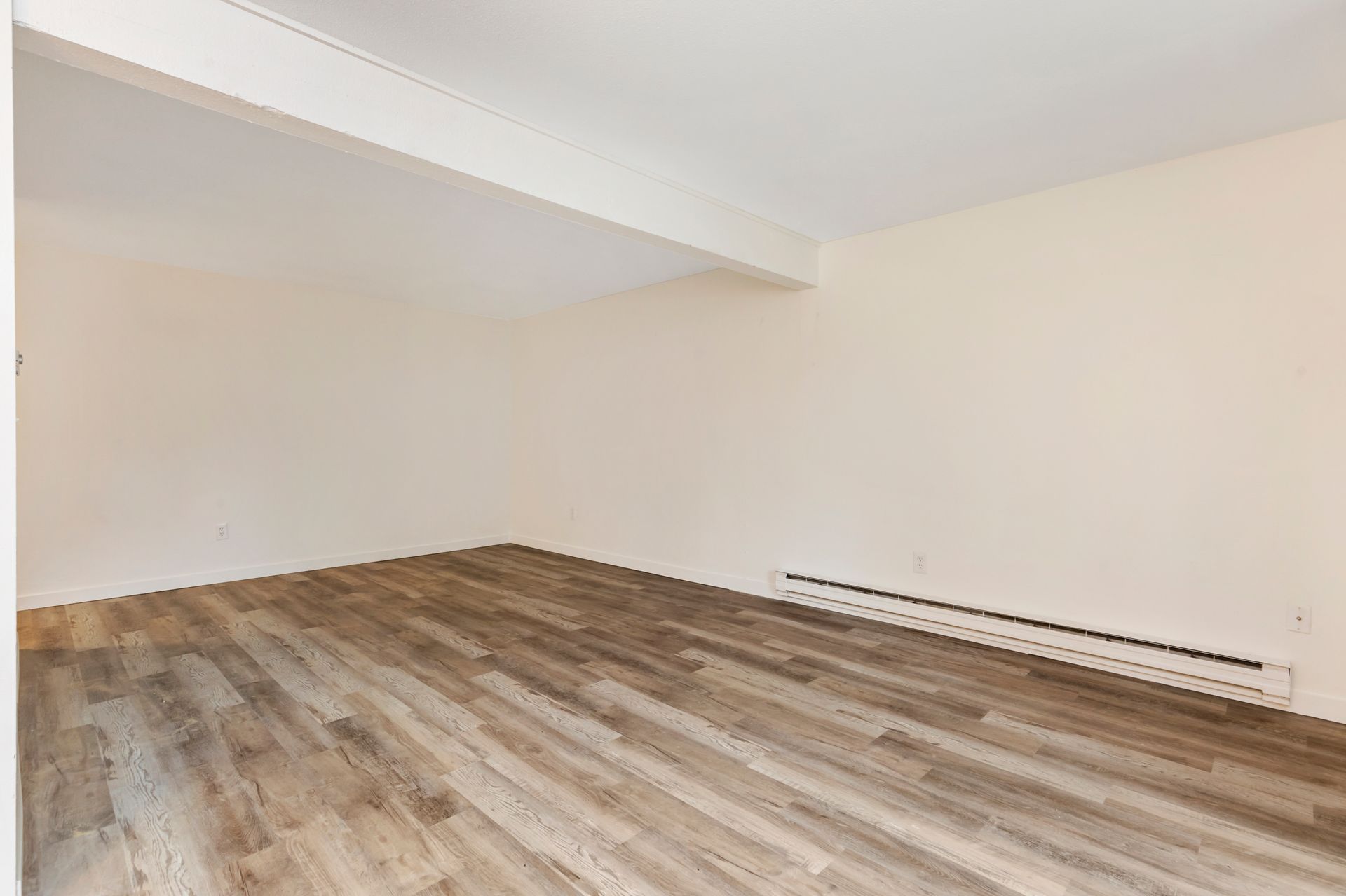 an empty room with hardwood floors and white walls .