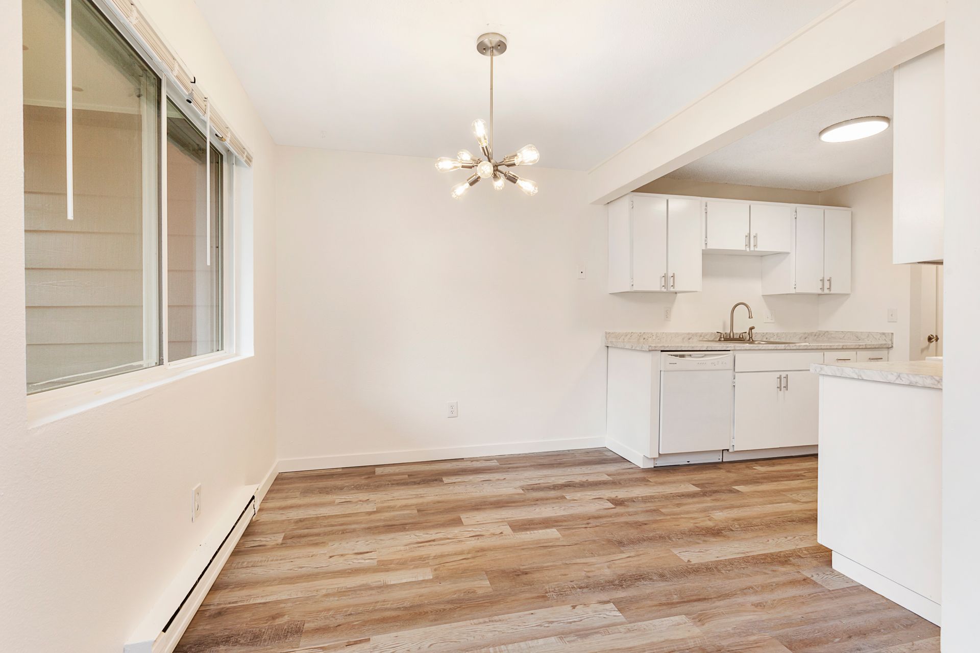 an empty room with hardwood floors and white cabinets