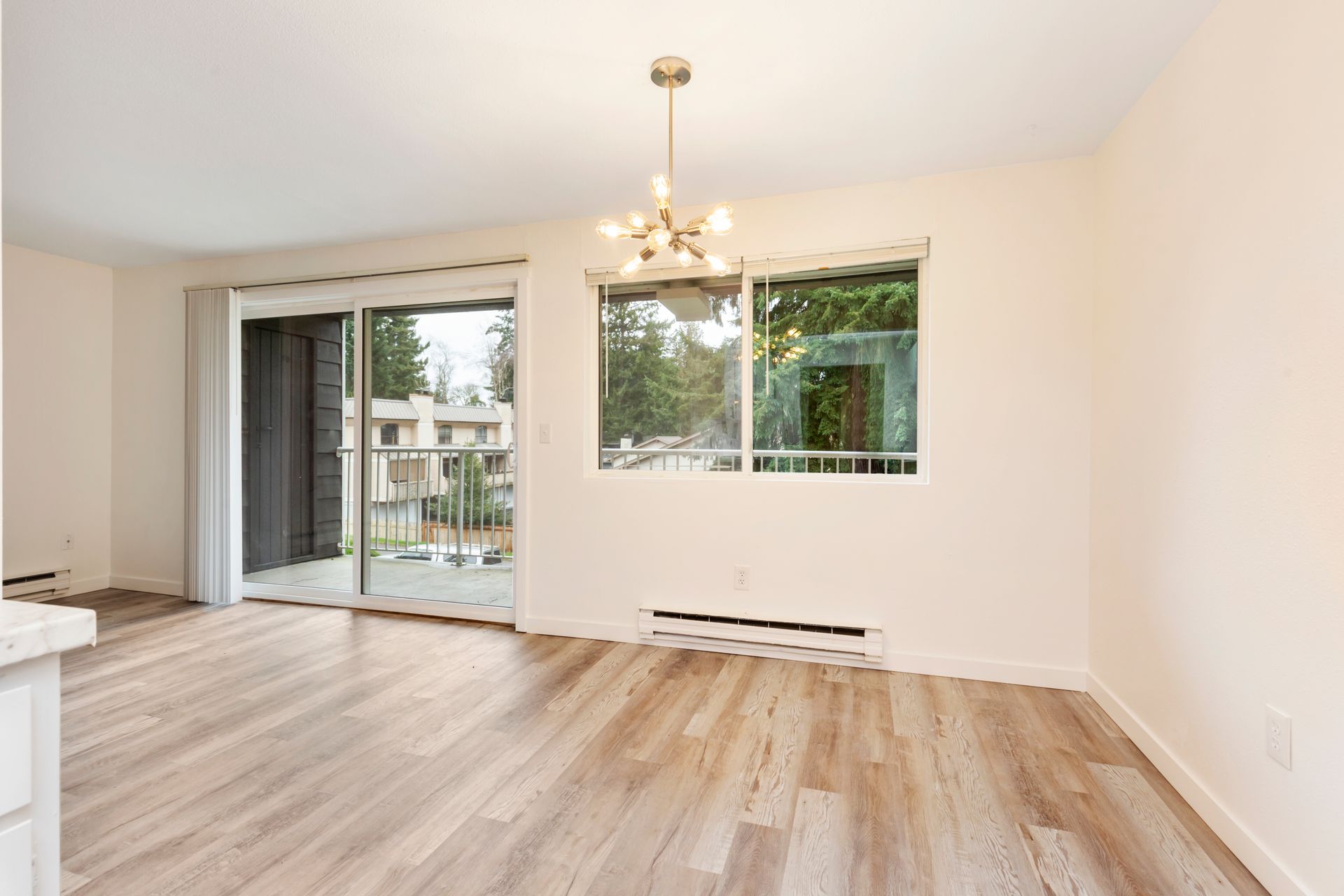 an empty living room with hardwood floors and sliding glass doors leading to a balcony .