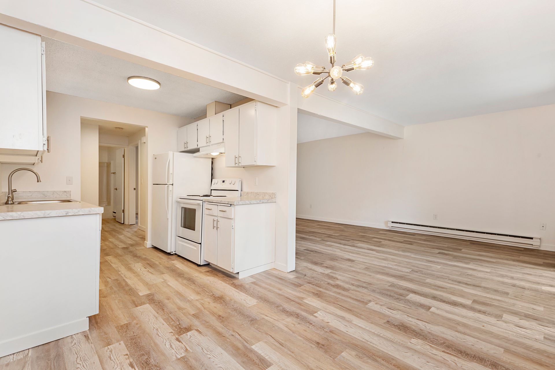 an empty apartment with a kitchen , dining room , and living room .