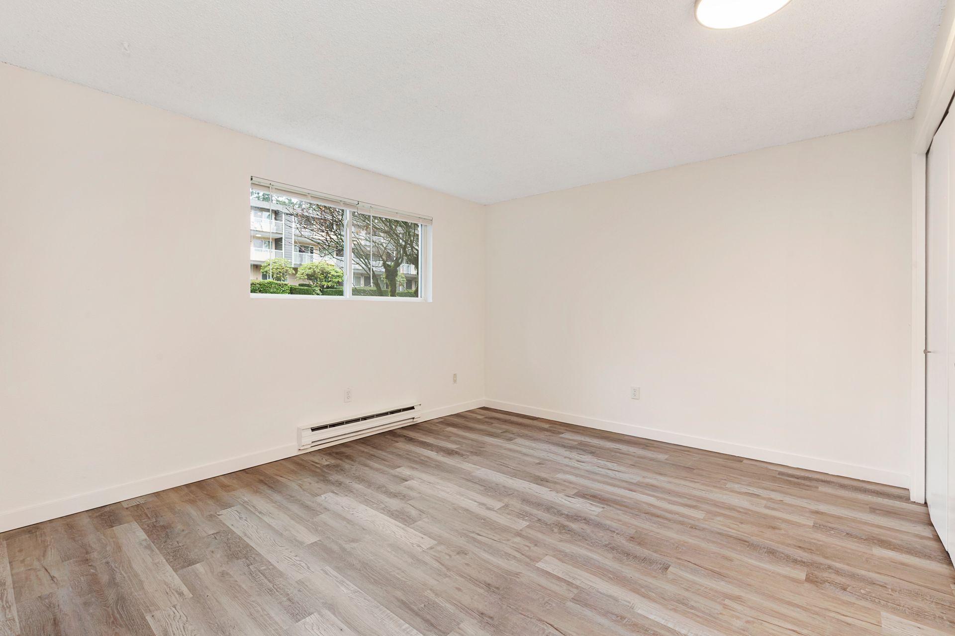 an empty room with hardwood floors and a window .
