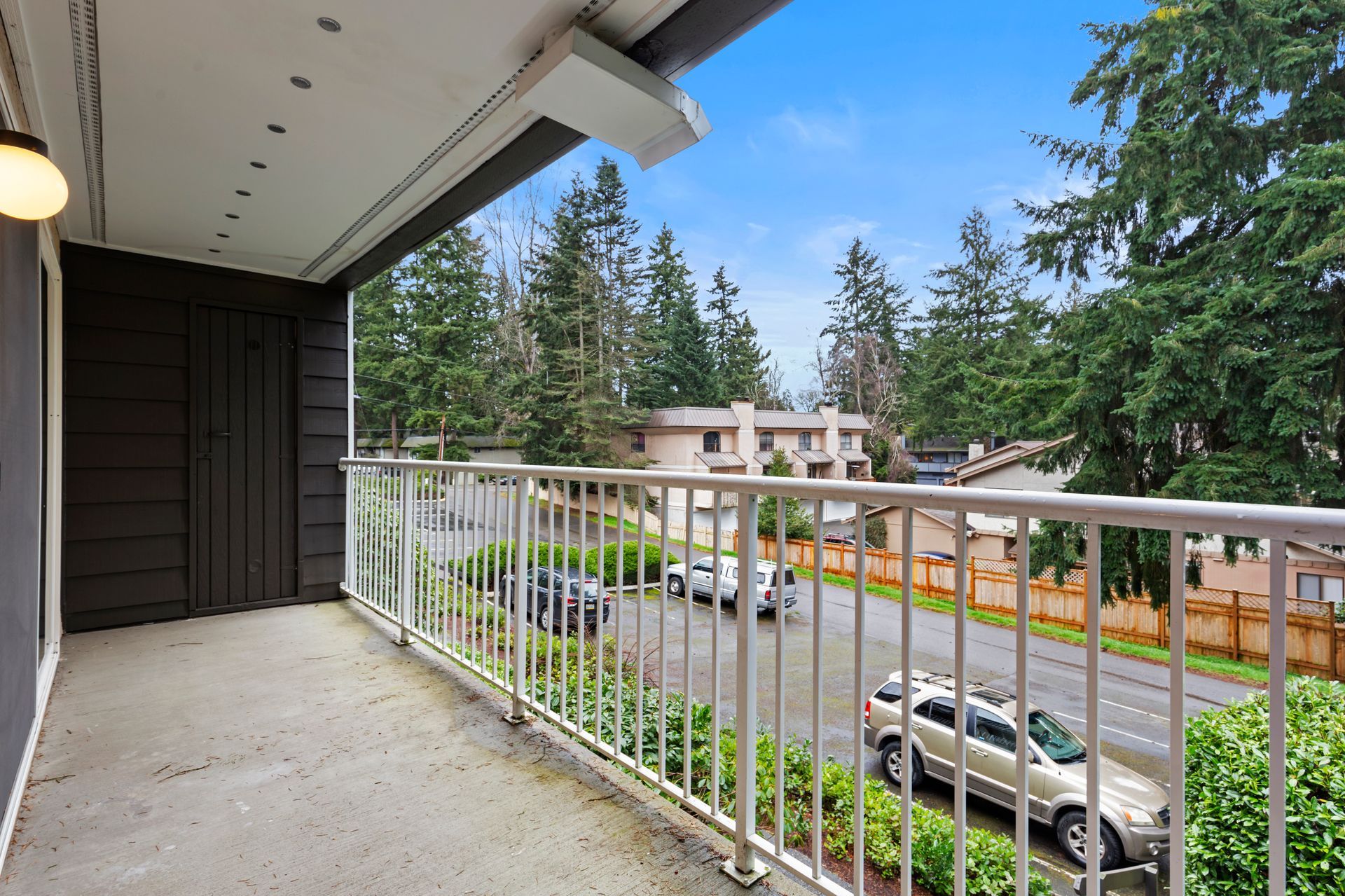 a balcony with a metal railing overlooking a street and trees .