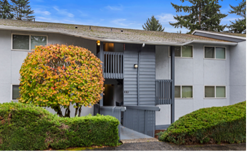 a gray apartment building with a tree in front of it