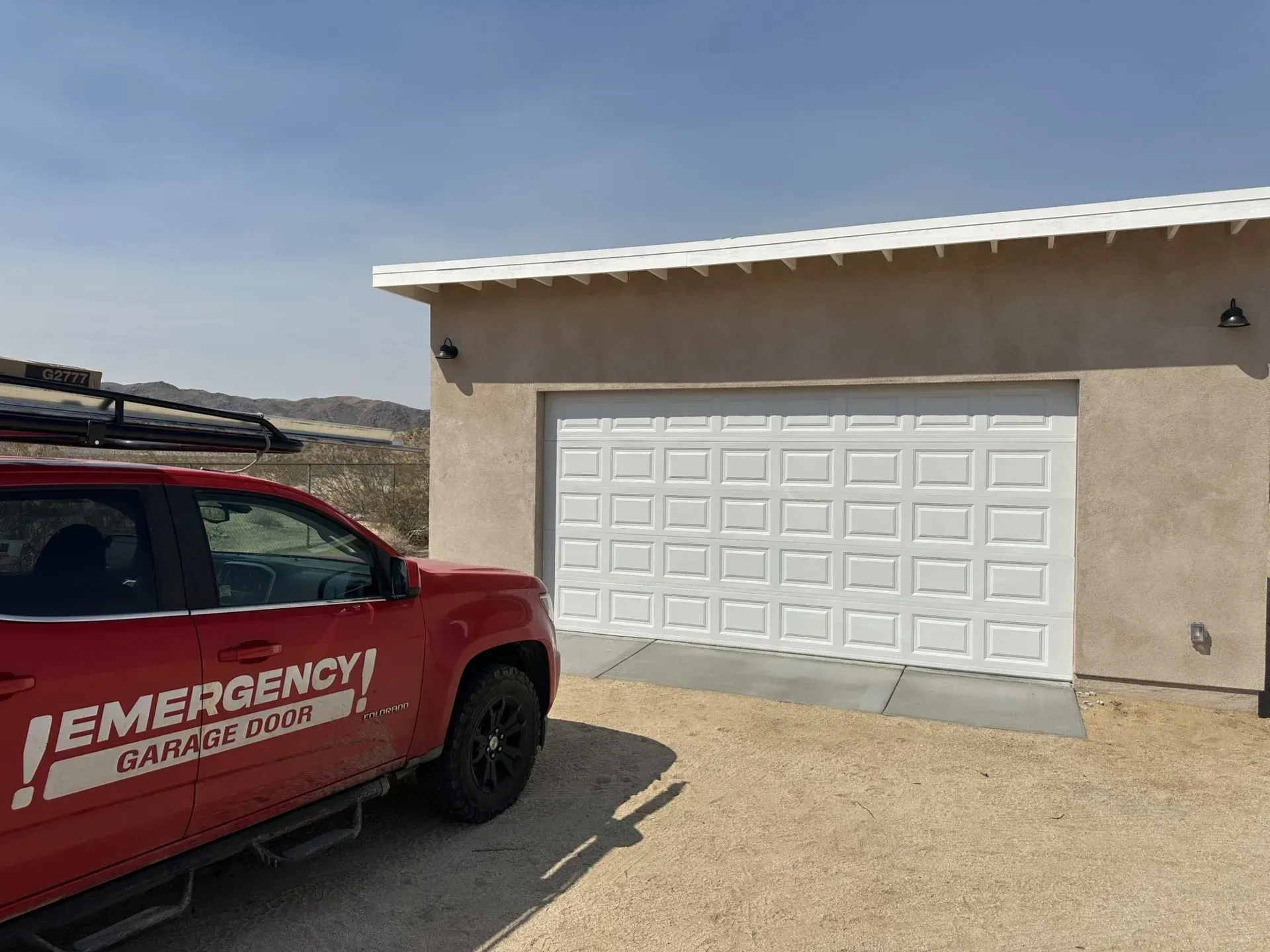 A red emergency garage door truck is parked in front of a garage door.