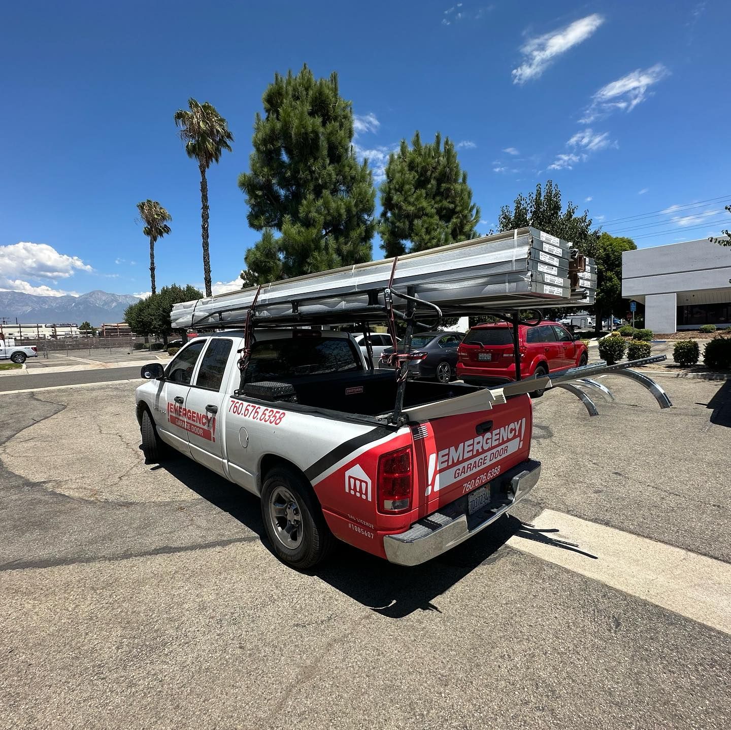A truck with a ladder in the back is parked in a parking lot.