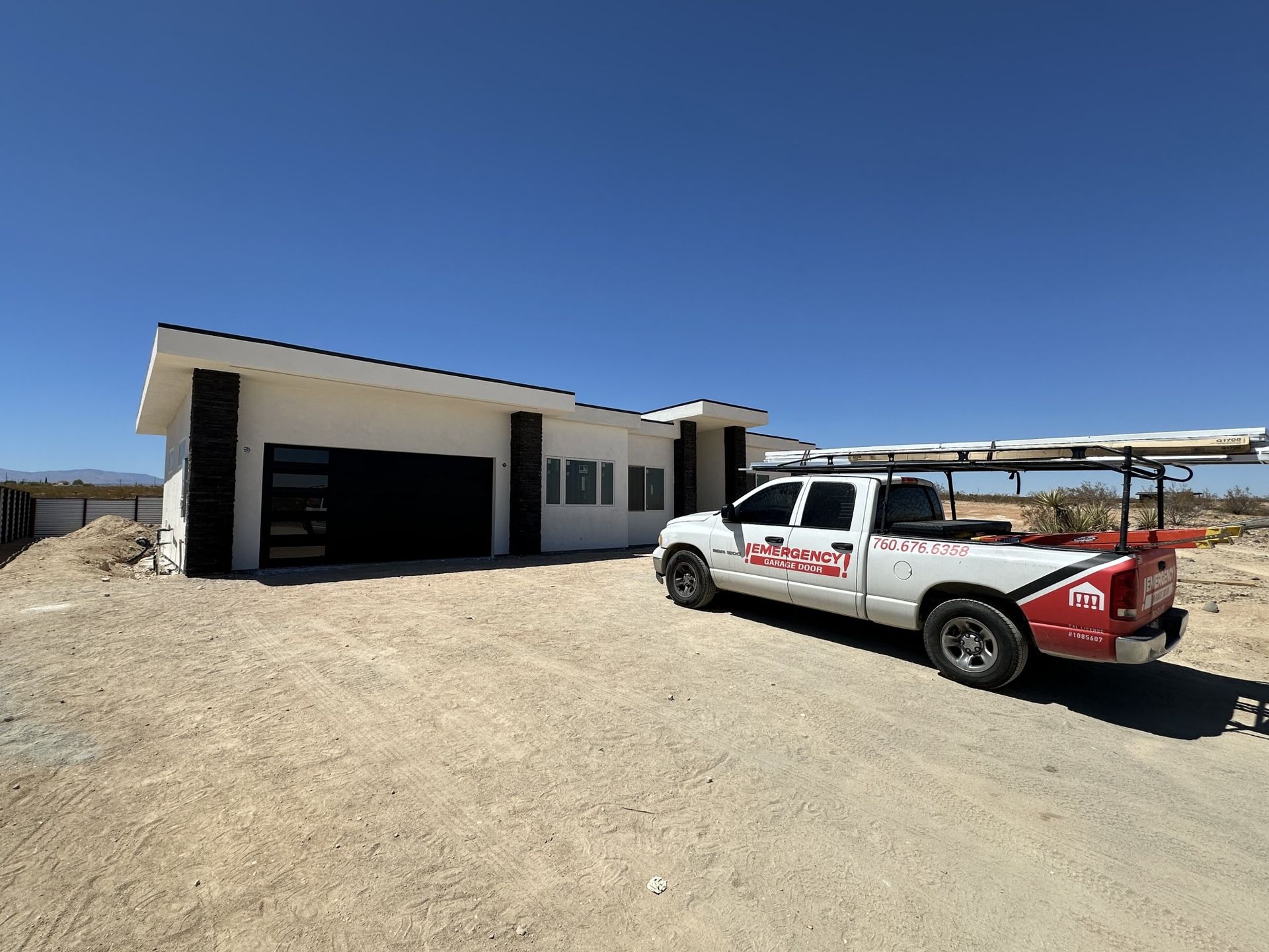 A white truck is parked in front of a house under construction.