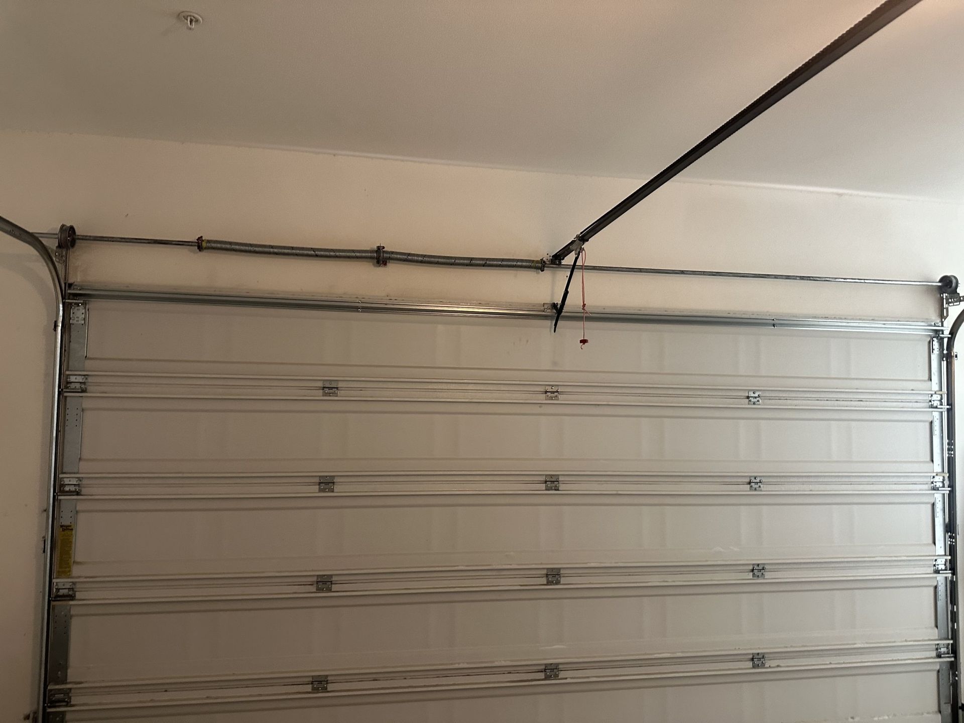 A white garage door with a metal frame is open in a garage.