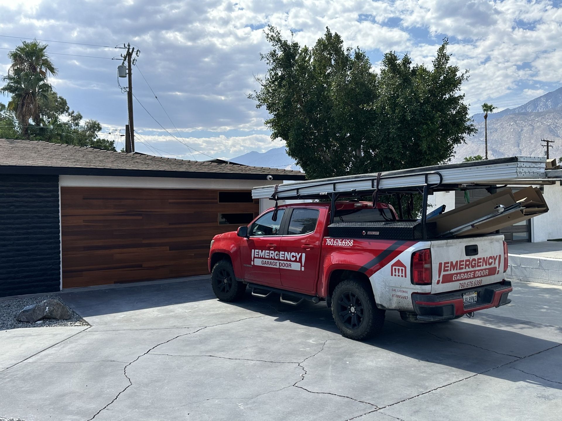 A red truck with a ladder on the back is parked in front of a house.