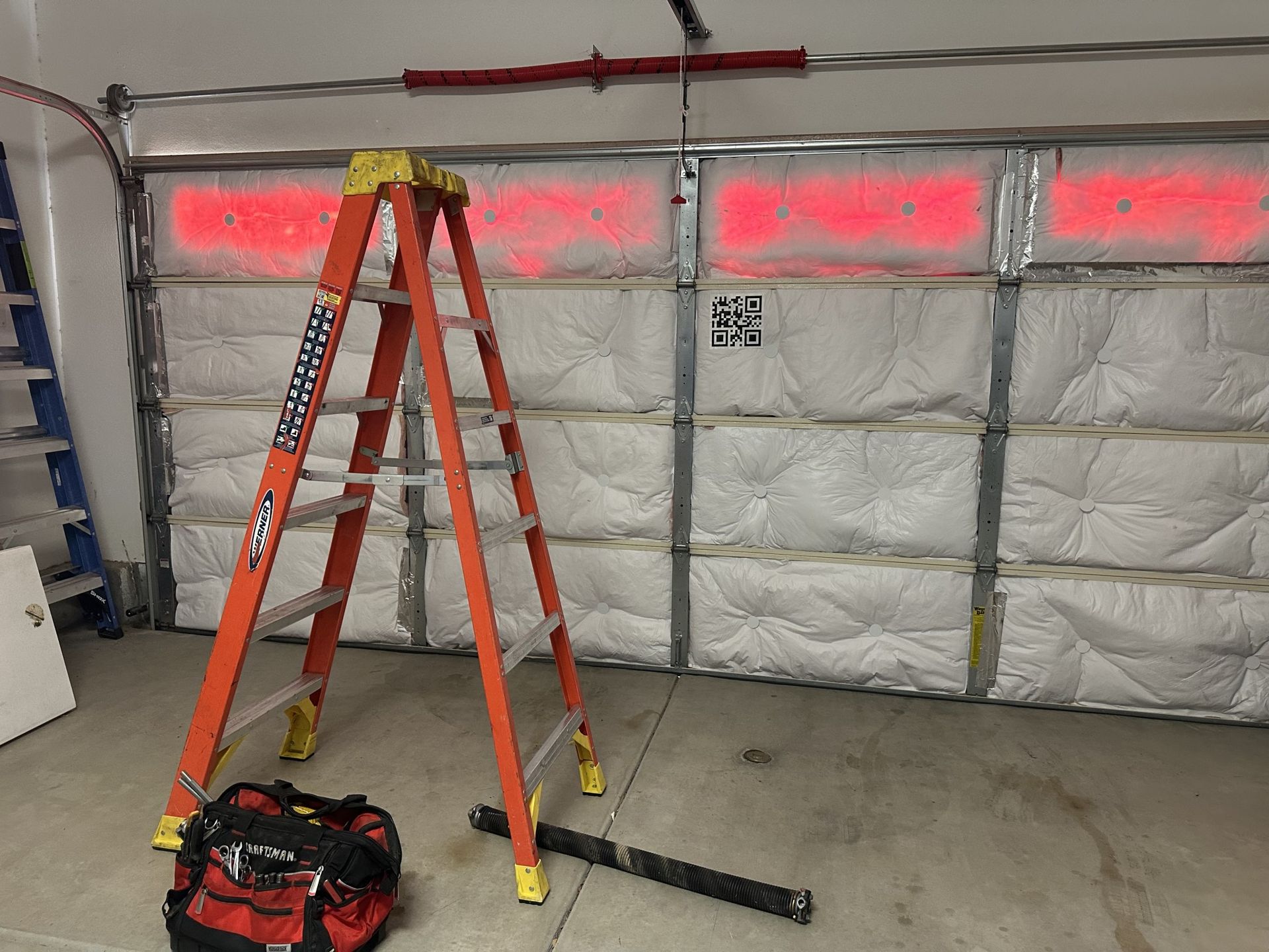 A ladder is sitting in front of a garage door.
