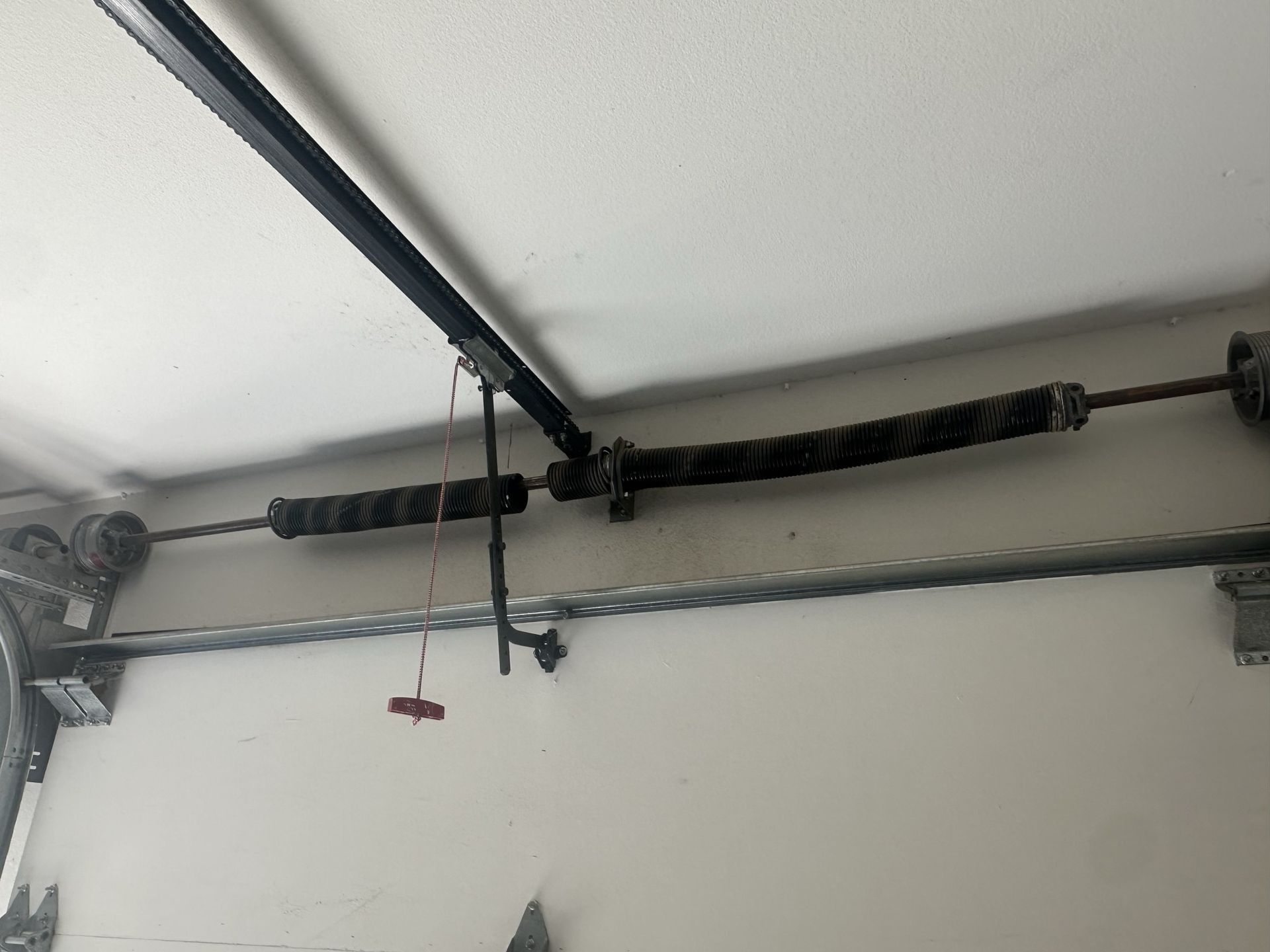 A garage door spring is hanging from the ceiling of a garage.